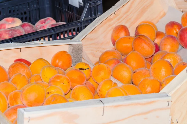Fresh peaches in a wooden box for sale at a farmers market. Fresh peaches — Stock Photo, Image