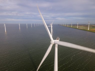 Bulutları ve mavi gökyüzü olan off-shore yel değirmeni parkı, okyanusta rüzgar türbinli drone hava manzaralı yel değirmeni.