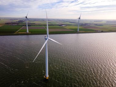 Bulutları ve mavi gökyüzü olan off-shore yel değirmeni parkı, okyanusta rüzgar türbinli drone hava manzaralı yel değirmeni.