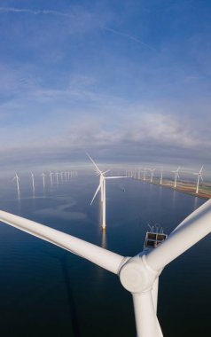 Bulutları ve mavi gökyüzü olan off-shore yel değirmeni parkı, okyanusta rüzgar türbinli drone hava manzaralı yel değirmeni.