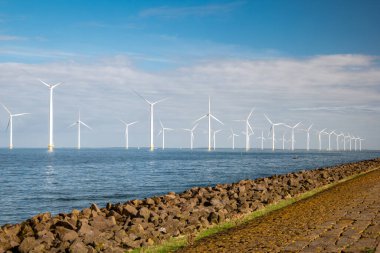 Bulutları ve mavi gökyüzü olan off-shore yel değirmeni parkı, okyanusta rüzgar türbinli drone hava manzaralı yel değirmeni.
