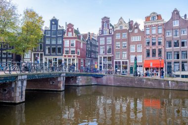 Amsterdam Hollanda 'da sonbahar mevsimi boyunca, Hollanda kanallarının yanında, kanalların etrafında renkli ağaçlar bulunan ve insanların güneşte dinlendiği şehir, restoran yüzünden caddeye döküldü.