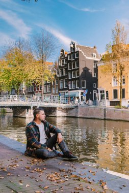 Amsterdam Hollanda sonbahar sezonu boyunca, iki erkek ve kadın Ekim ayında kanal boyunca turuncu renklerle Amsterdam şehrini ziyaret etti.