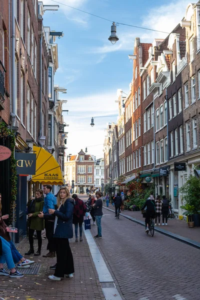 Amsterdam Niederlande im Herbst Herbstsaison in der Stadt entlang der holländischen Kanäle mit bunten Bäumen rund um die Kanäle und Menschen, die sich in der Sonne entspannen draußen auf der Straße, weil das Restaurant — Stockfoto