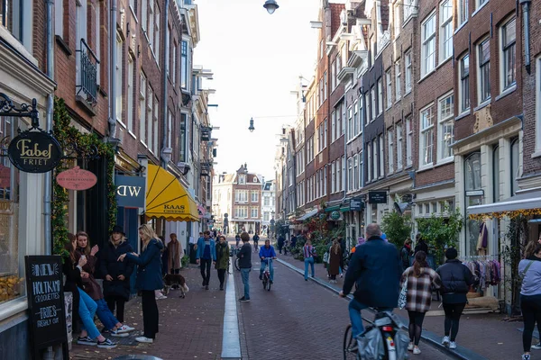 Amsterdam Niederlande im Herbst Herbstsaison in der Stadt entlang der holländischen Kanäle mit bunten Bäumen rund um die Kanäle und Menschen, die sich in der Sonne entspannen draußen auf der Straße, weil das Restaurant — Stockfoto