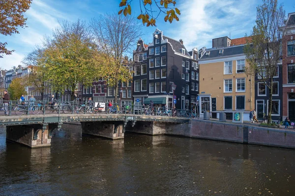 Amsterdam Paesi Bassi durante la stagione autunnale in città lungo i canali olandesi con alberi colorati intorno ai canali e le persone che si rilassano al sole outsied sulla strada perché il ristorante — Foto Stock