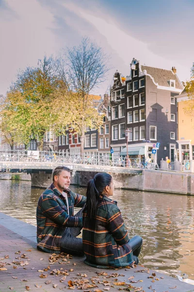 Amsterdam Países Bajos durante la temporada de otoño, pareja de hombres y mujeres visitan la ciudad de Amsterdam con colores naranjas junto al canal en octubre —  Fotos de Stock