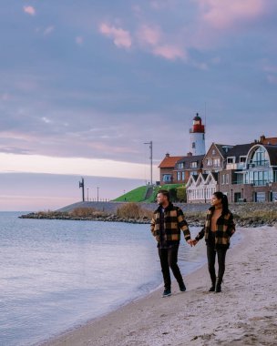 Urk Flevoland Holland, iki erkek ve kadın Urk Hollanda 'nın küçük balıkçı köyü limanında gün batımını izliyorlar.