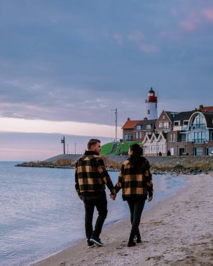 Urk Flevoland Holland, iki erkek ve kadın Urk Hollanda 'nın küçük balıkçı köyü limanında gün batımını izliyorlar.