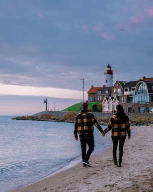 Urk Flevoland Holland, iki erkek ve kadın Urk Hollanda 'nın küçük balıkçı köyü limanında gün batımını izliyorlar.