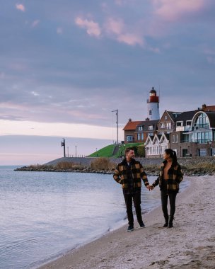Urk Flevoland Holland, iki erkek ve kadın Urk Hollanda 'nın küçük balıkçı köyü limanında gün batımını izliyorlar.