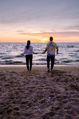 Sahilde atlama egzersizi yapan insanlar, Hollanda sahillerinde birlikte egzersiz yapan birkaç erkek ve kadın.