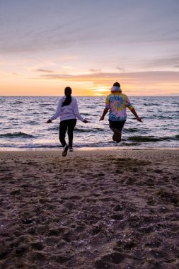 Sahilde atlama egzersizi yapan insanlar, Hollanda sahillerinde birlikte egzersiz yapan birkaç erkek ve kadın.