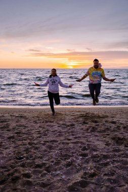 Sahilde atlama egzersizi yapan insanlar, Hollanda sahillerinde birlikte egzersiz yapan birkaç erkek ve kadın.