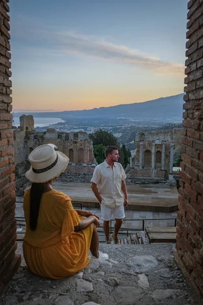 Pareja de hombres y mujeres visitan Ruinas del teatro griego antiguo en Taormina en el fondo del volcán Etna, Italia. Taormina situado en la ciudad metropolitana de Messina, en la costa este de la isla de Sicilia. — Foto de Stock