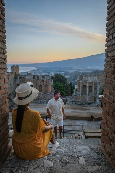 Pareja de hombres y mujeres visitan Ruinas del teatro griego antiguo en Taormina en el fondo del volcán Etna, Italia. Taormina situado en la ciudad metropolitana de Messina, en la costa este de la isla de Sicilia. — Foto de Stock