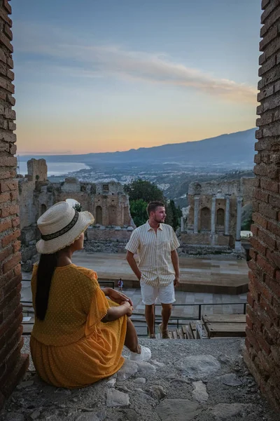 Pareja de hombres y mujeres visitan Ruinas del teatro griego antiguo en Taormina en el fondo del volcán Etna, Italia. Taormina situado en la ciudad metropolitana de Messina, en la costa este de la isla de Sicilia. — Foto de Stock