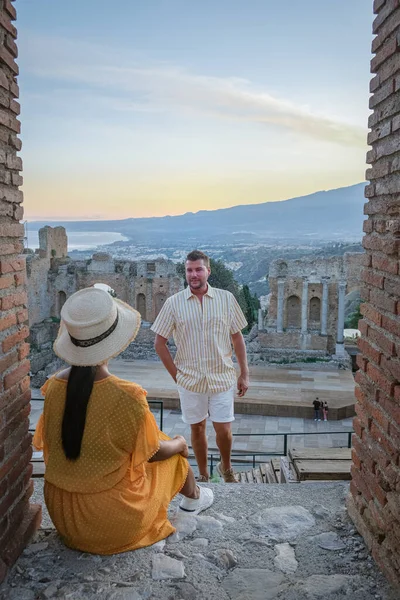 Pareja de hombres y mujeres visitan Ruinas del teatro griego antiguo en Taormina en el fondo del volcán Etna, Italia. Taormina situado en la ciudad metropolitana de Messina, en la costa este de la isla de Sicilia. — Foto de Stock