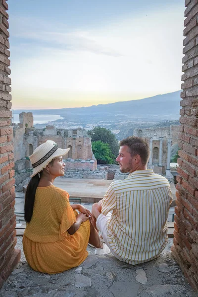 Pareja de hombres y mujeres visitan Ruinas del teatro griego antiguo en Taormina en el fondo del volcán Etna, Italia. Taormina situado en la ciudad metropolitana de Messina, en la costa este de la isla de Sicilia. — Foto de Stock
