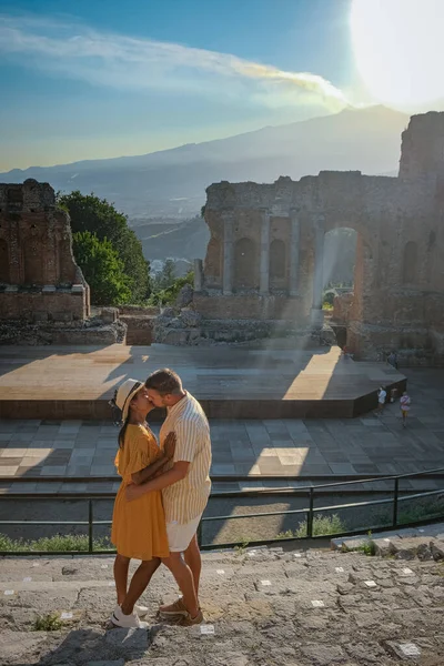 Paar Männer und Frauen besuchen Ruinen des antiken griechischen Theaters in Taormina vor dem Hintergrund des Vulkans Ätna, Italien. Taormina liegt in der Metropolstadt Messina, an der Ostküste der Insel Sizilien. — Stockfoto