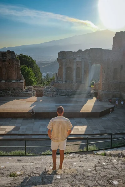 Pareja de hombres y mujeres visitan Ruinas del teatro griego antiguo en Taormina en el fondo del volcán Etna, Italia. Taormina situado en la ciudad metropolitana de Messina, en la costa este de la isla de Sicilia. — Foto de Stock