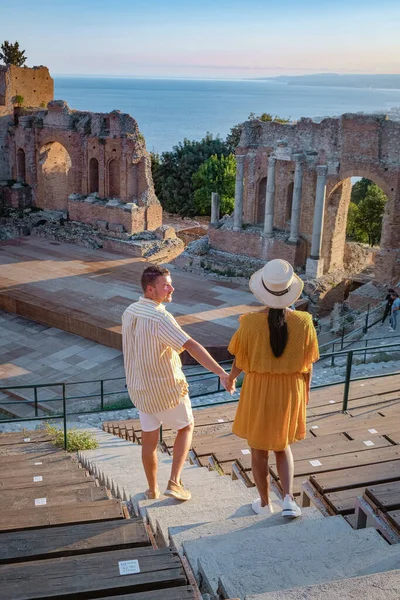 Pareja de hombres y mujeres visitan Ruinas del teatro griego antiguo en Taormina en el fondo del volcán Etna, Italia. Taormina situado en la ciudad metropolitana de Messina, en la costa este de la isla de Sicilia. — Foto de Stock