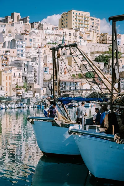 Sciacca Sicilia barche da pesca e persone riparano le reti nella colorata città di Sciacca affacciata sul suo porto. Provincia di Agrigento, Sicilia — Foto Stock