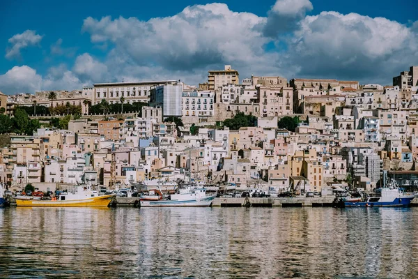Шакка Сицилия рыбацкие лодки и люди ремонтируют сети в красочном городе Шакка с видом на его гавань. Провинция Агридженто — стоковое фото