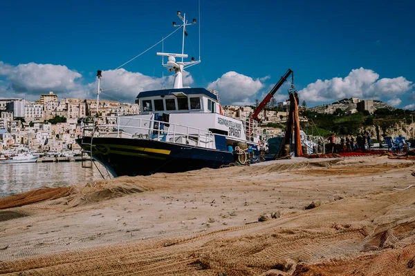 Sciacca Sycylia łodzie rybackie i ludzie naprawiają sieci w kolorowym mieście Sciacca z widokiem na port. Prowincja Agrigento, Sycylia — Zdjęcie stockowe