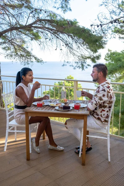 Pareja desayunando al aire libre en la terraza de Sicilia con vistas al océano —  Fotos de Stock