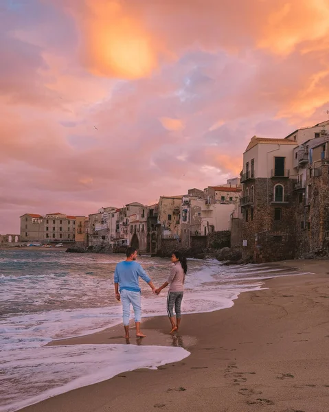 Cefalu Sicilia, pareja viendo atardecer en la playa de Cefalu Sicilia Italia, hombres y mujeres de mediana edad de vacaciones Sicilia — Foto de Stock