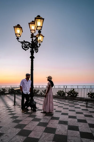 Taormina Sicilia, pareja de hombres y mujeres de mediana edad observando el amanecer en el casco antiguo de Taormina Sicilia — Foto de Stock