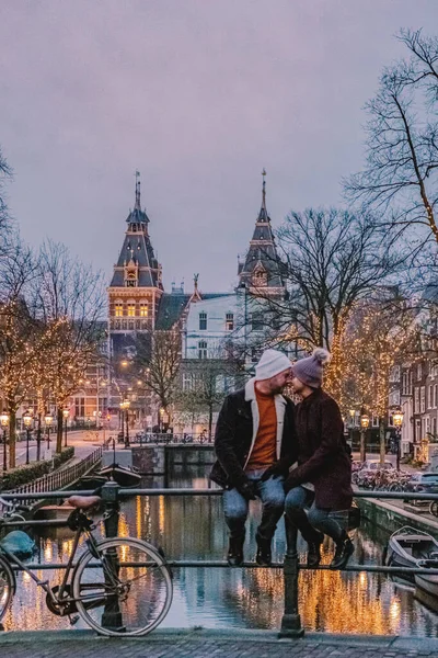Pareja en viaje de la ciudad Amsterdam Países Bajos canales con luces de Navidad durante diciembre, canal centro histórico de Amsterdam por la noche —  Fotos de Stock