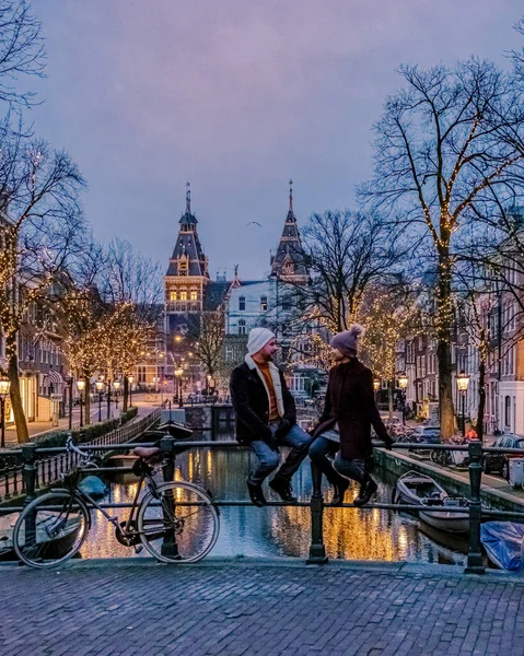 Paar auf Städtereise Amsterdam Niederlande Grachten mit Weihnachtsbeleuchtung im Dezember, Kanal historischen Zentrum von Amsterdam bei Nacht — Stockfoto
