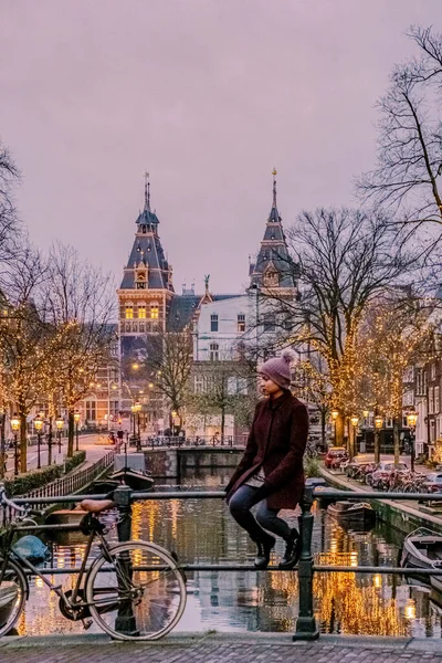 Pareja en viaje de la ciudad Amsterdam Países Bajos canales con luces de Navidad durante diciembre, canal centro histórico de Amsterdam por la noche — Foto de Stock