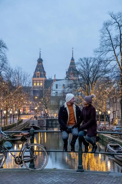 Pareja en viaje de la ciudad Amsterdam Países Bajos canales con luces de Navidad durante diciembre, canal centro histórico de Amsterdam por la noche —  Fotos de Stock