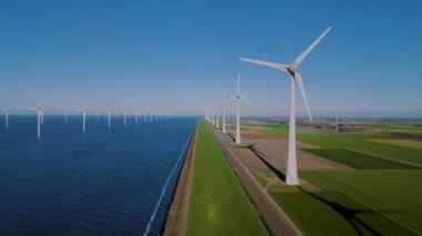 Hollanda Flevoland 'daki yel değirmeni türbinleri Hollanda' daki ijsselmeer gölünün yanındaki yeşil enerji rüzgar türbinleri.