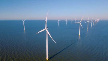 Hollanda Flevoland 'daki yel değirmeni türbinleri Hollanda' daki ijsselmeer gölünün yanındaki yeşil enerji rüzgar türbinleri.
