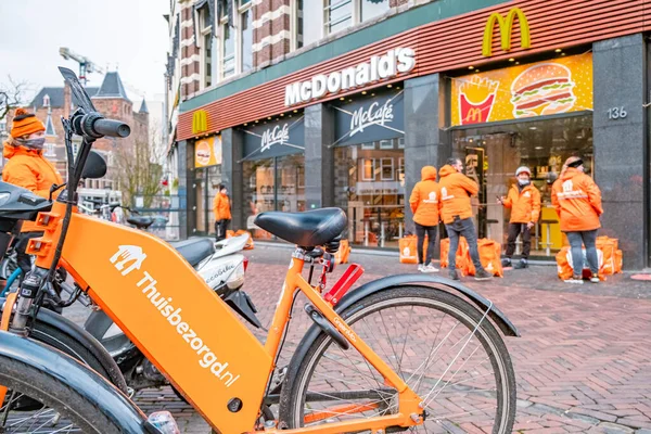 Utrecht Netherlands Thuisbezorgd and Deliveroo food couriers wait in Utrecht, Netherlands. 자전거 식품의 배달은 세계적 대유행 코로나 바이러스의 확산을 막는 동안 위트레흐트에서 인기가 있다 19 — 스톡 사진
