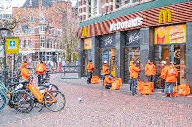 Utrecht Hollanda Thuisbezorgd ve Utrecht, Hollanda 'da yemek kuryeleri bekliyor. Bisikletli gıda teslimatı Utrecht 'te salgın koronavirüs salgını sırasında popülerdir.