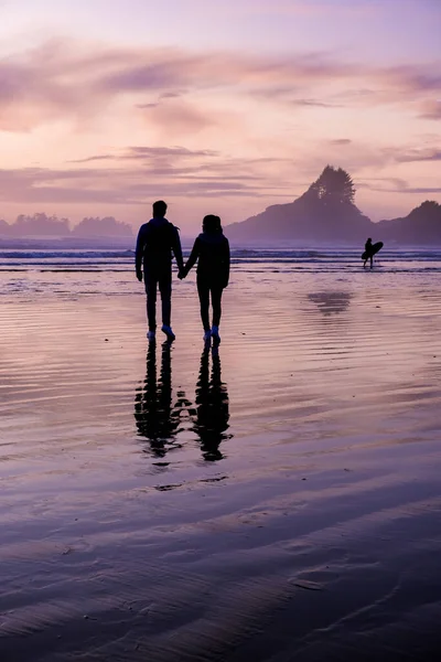 Casal homens e mulher de meia idade assistindo pôr do sol na praia de Tofino Vancouver Island Canadá, belo pôr do sol na praia com cores roxas cor de rosa no céu — Fotografia de Stock