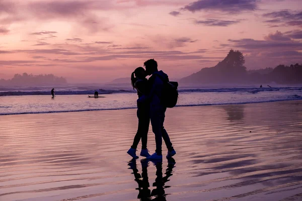 Casal homens e mulher de meia idade assistindo pôr do sol na praia de Tofino Vancouver Island Canadá, belo pôr do sol na praia com cores roxas cor de rosa no céu — Fotografia de Stock