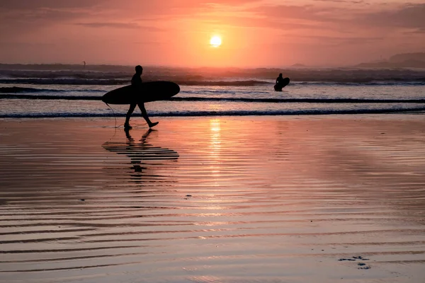 Tofino Vancouver Island Pacifische kust, surfers met boord bij zonsondergang op het strand, surfers silhouet Canada Vancouver Island Tofino. — Stockfoto