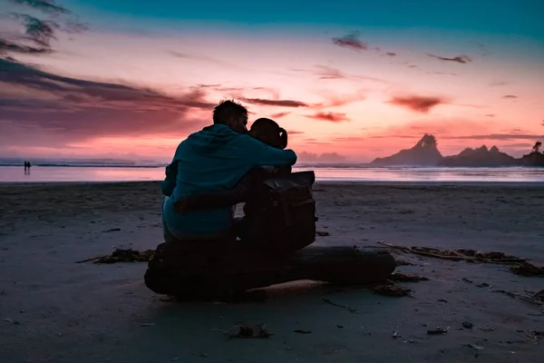 Coppia di uomini e donne di mezza età guardando il tramonto sulla spiaggia di Tofino Vancouver Island Canada, bellissimo tramonto sulla spiaggia con colori rosa viola nel cielo — Foto Stock