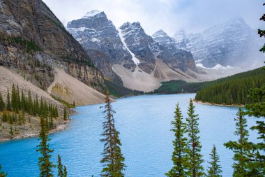 Gün batımındaki güzel Moraine Gölü, Moraine Gölü 'nün güzel turkuaz suları Kanada Banff Ulusal Parkı' ndaki karlı dağlarla kaplı.