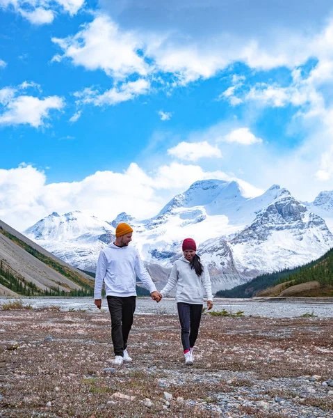 Pareja de hombres y mujeres de mediana edad senderismo en las Rocosas canadienses cerca del parque nacional Alberta Banff con montañas nevadas —  Fotos de Stock