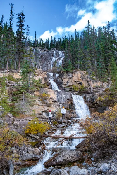 Tangle Creek Falls i Jaspers nationalpark, Alberta, Kanada, par män och kvinnor i medelåldern vandrar upp till vattenfall i naturen — Stockfoto