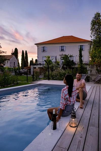 Pareja de hombres y mujeres que se relajan junto a la piscina en una villa de Francia en la Provenza, hombre y mujer en traje de baño y bañador en la piscina durante las vacaciones en Francia —  Fotos de Stock