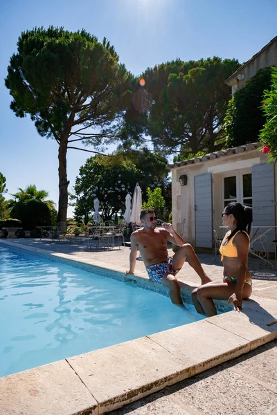 Coppia di uomini e donne che si rilassano a bordo piscina in una villa francese in Provenza, uomo e donna in costume da bagno e costume da bagno a bordo piscina durante le vacanze in Francia — Foto Stock
