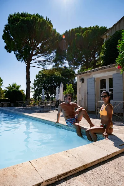 Coppia di uomini e donne che si rilassano a bordo piscina in una villa francese in Provenza, uomo e donna in costume da bagno e costume da bagno a bordo piscina durante le vacanze in Francia — Foto Stock